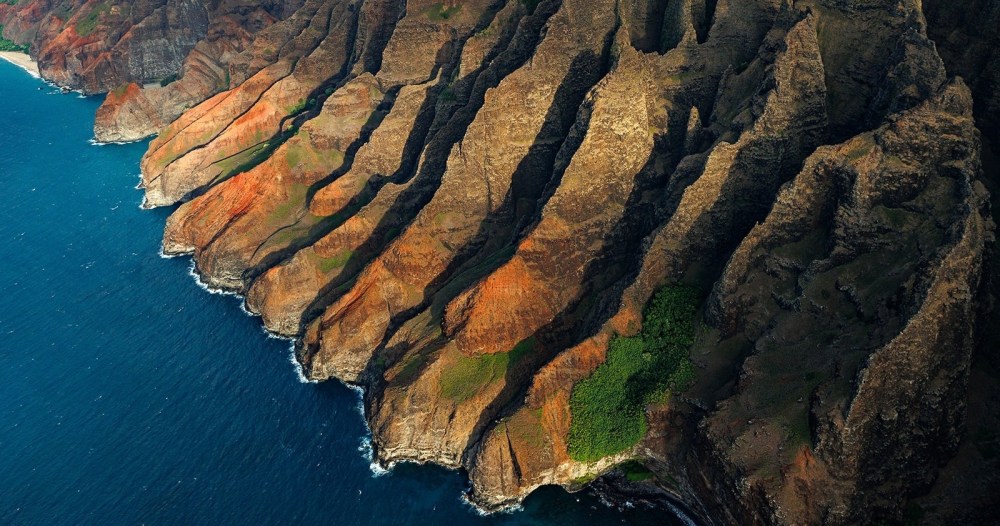 a rocky cliff with water and a mountain in the background
