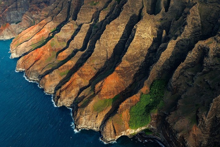 a rocky cliff with water and a mountain in the background